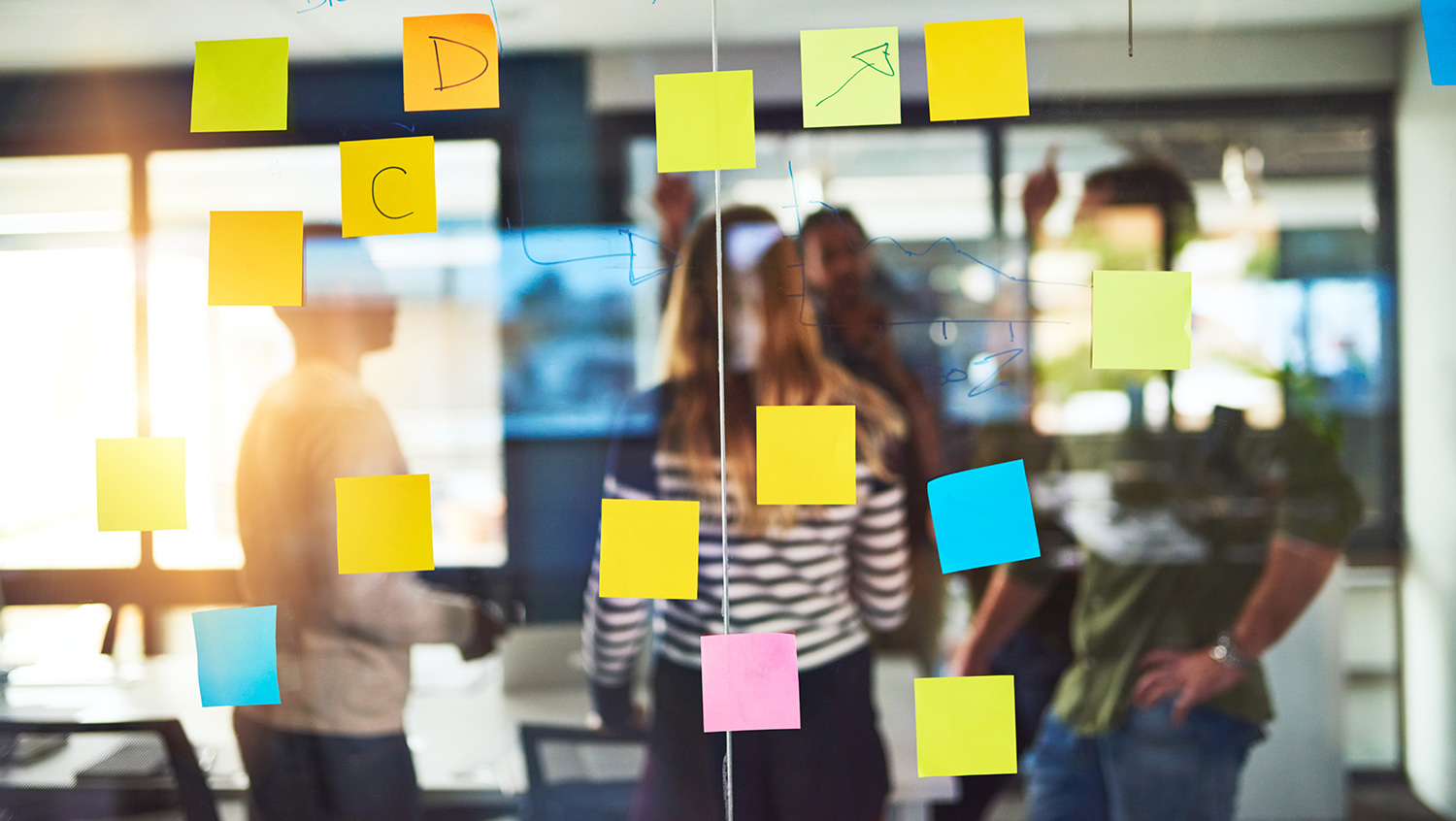 Equipo trabajando en sesión de design thinking con notas adhesivas en una sala de reuniones
