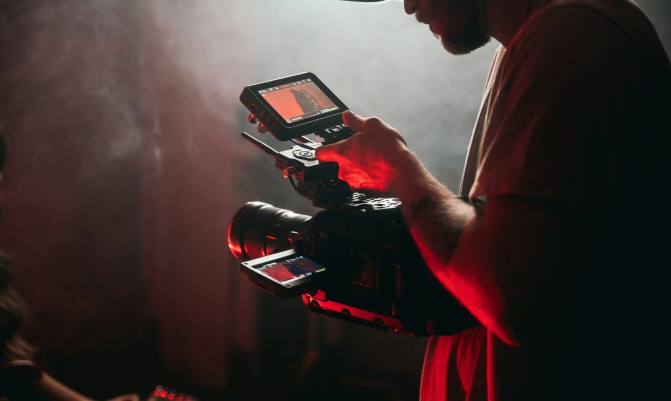 man in white t-shirt holding black video camera