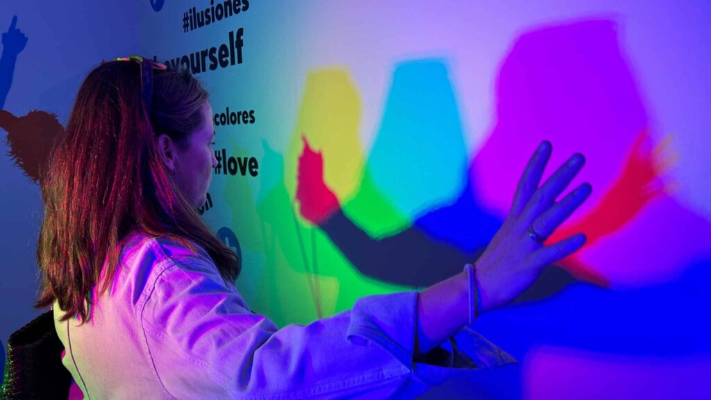 Mujer interactuando con luces y sombras de colores en una instalación digital