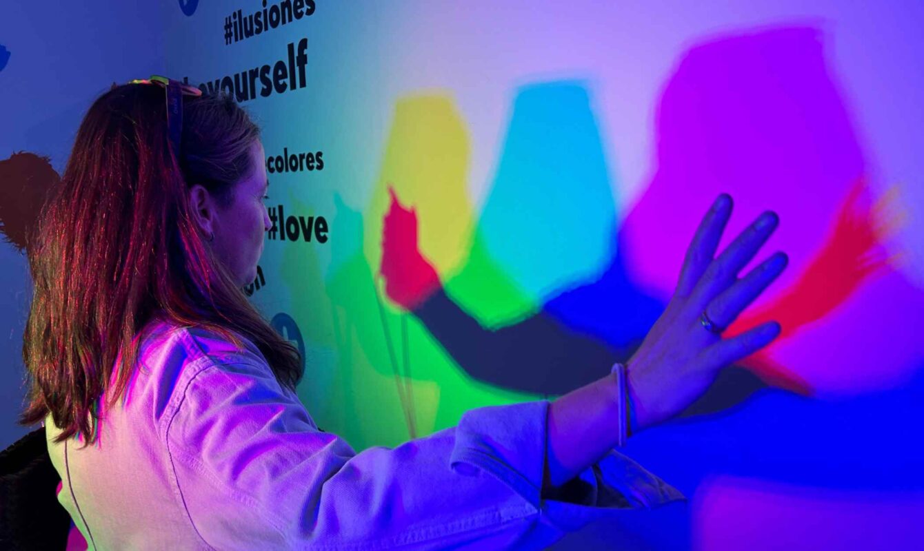 Mujer interactuando con luces y sombras de colores en una instalación digital