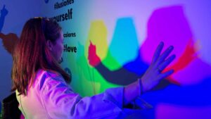Mujer interactuando con luces y sombras de colores en una instalación digital