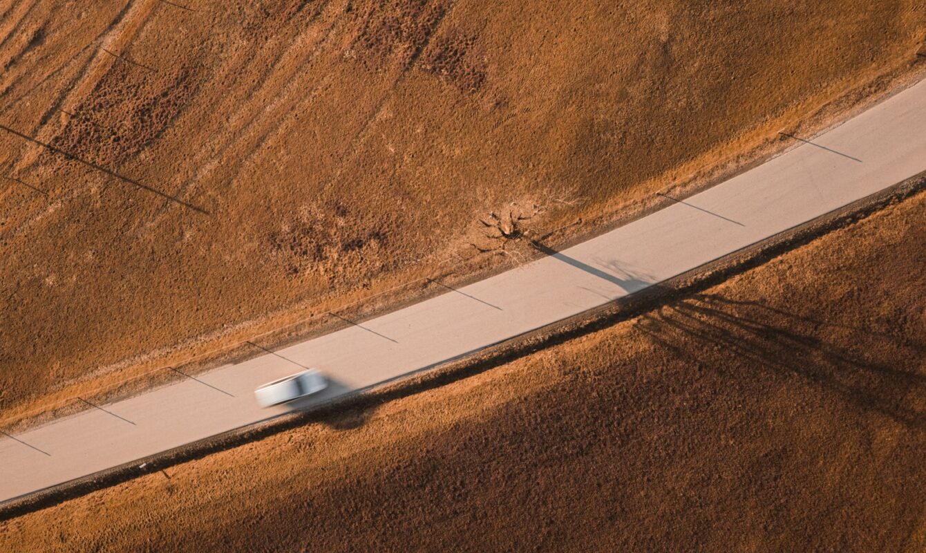 A car speeds along a road through a field.
