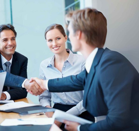 Ejecutivos estrechando manos tras una reunión de negociación empresarial.