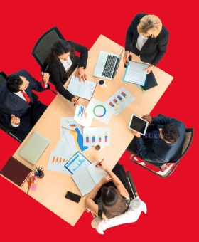 Reunión estratégica de ejecutivos analizando gráficos financieros en una operación de fusión o adquisición.