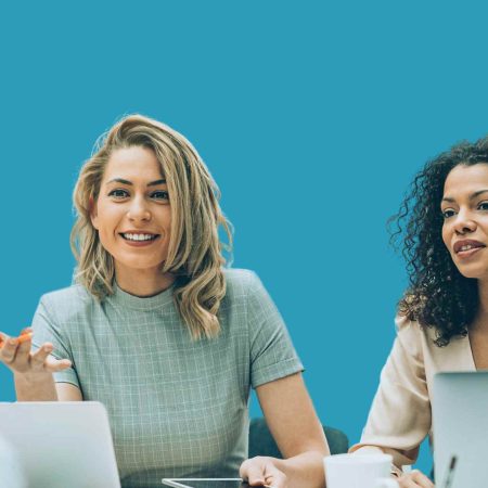 Mujer liderando conversación en una reunión de equipo con fondo azul.
