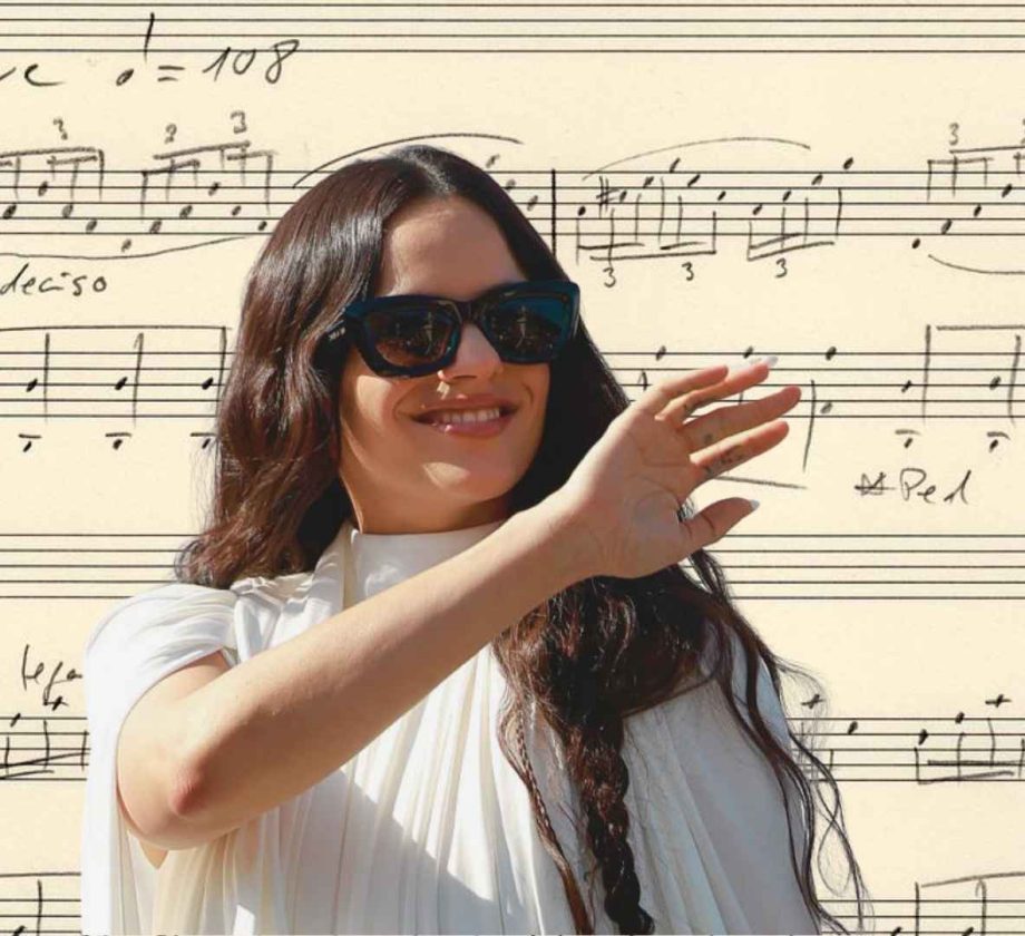 Rosalía sonríe vestida de blanco frente a una imagen de la partitura manuscrita de Berghain como fondo.