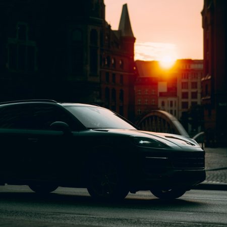 A dark car silhouetted by the setting sun.