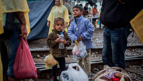 Niños refugiados con alimentos y agua en una zona de conflicto, retrato de la labor humanitaria de ONG.