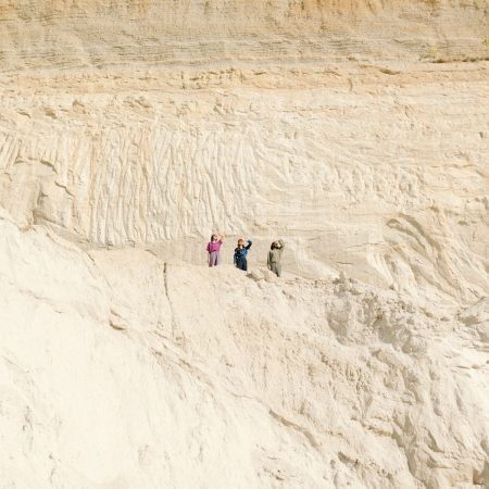 A group of people standing on top of a sandy hill