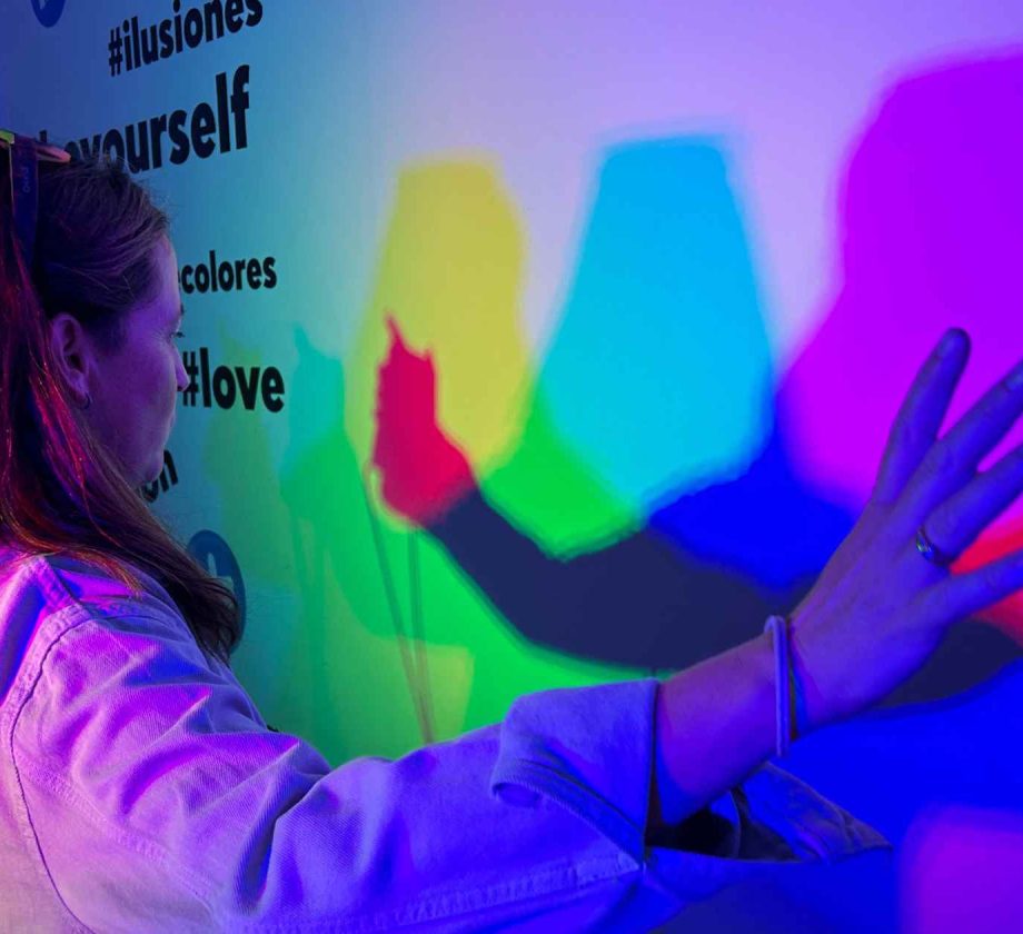 Mujer interactuando con luces y sombras de colores en una instalación digital